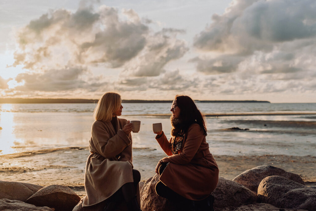 Två personer dricker te vid stranden i solnedgång – tips för mentalt välmående under mörka månaderna